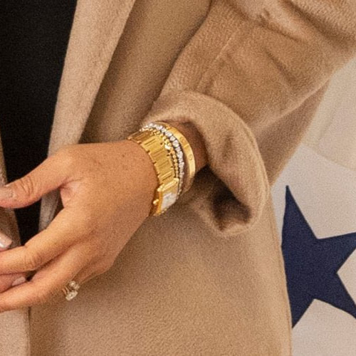 Meghan Markle wears Princess Diana's Gold Cartier Tank Française Watch, gold Jennifer Meyer mini bezel tennis bracelet, Princess Diana's Diamond Tennis Bracelet, and gold Cartier 'Love' Bracelet.